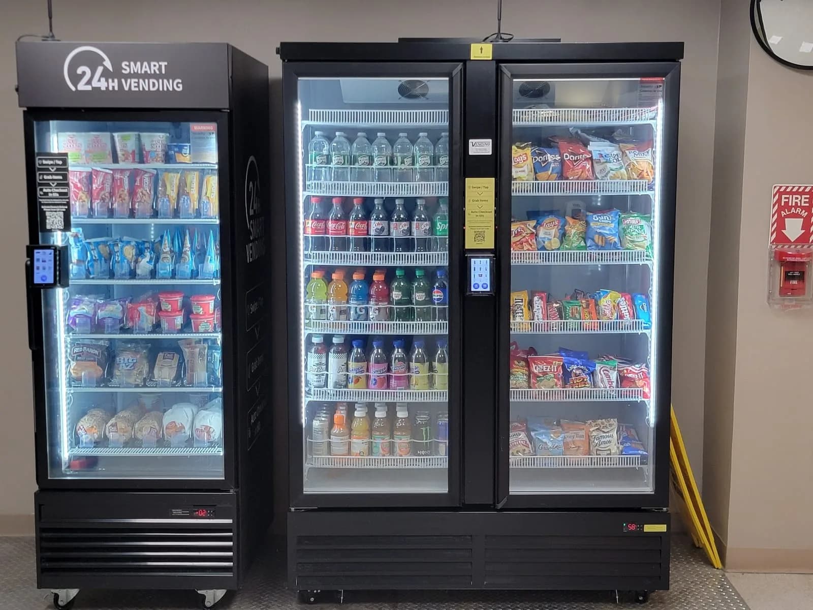 Unattended 24-hour smart market with open shelving and a glass-front cooler in an office breakroom